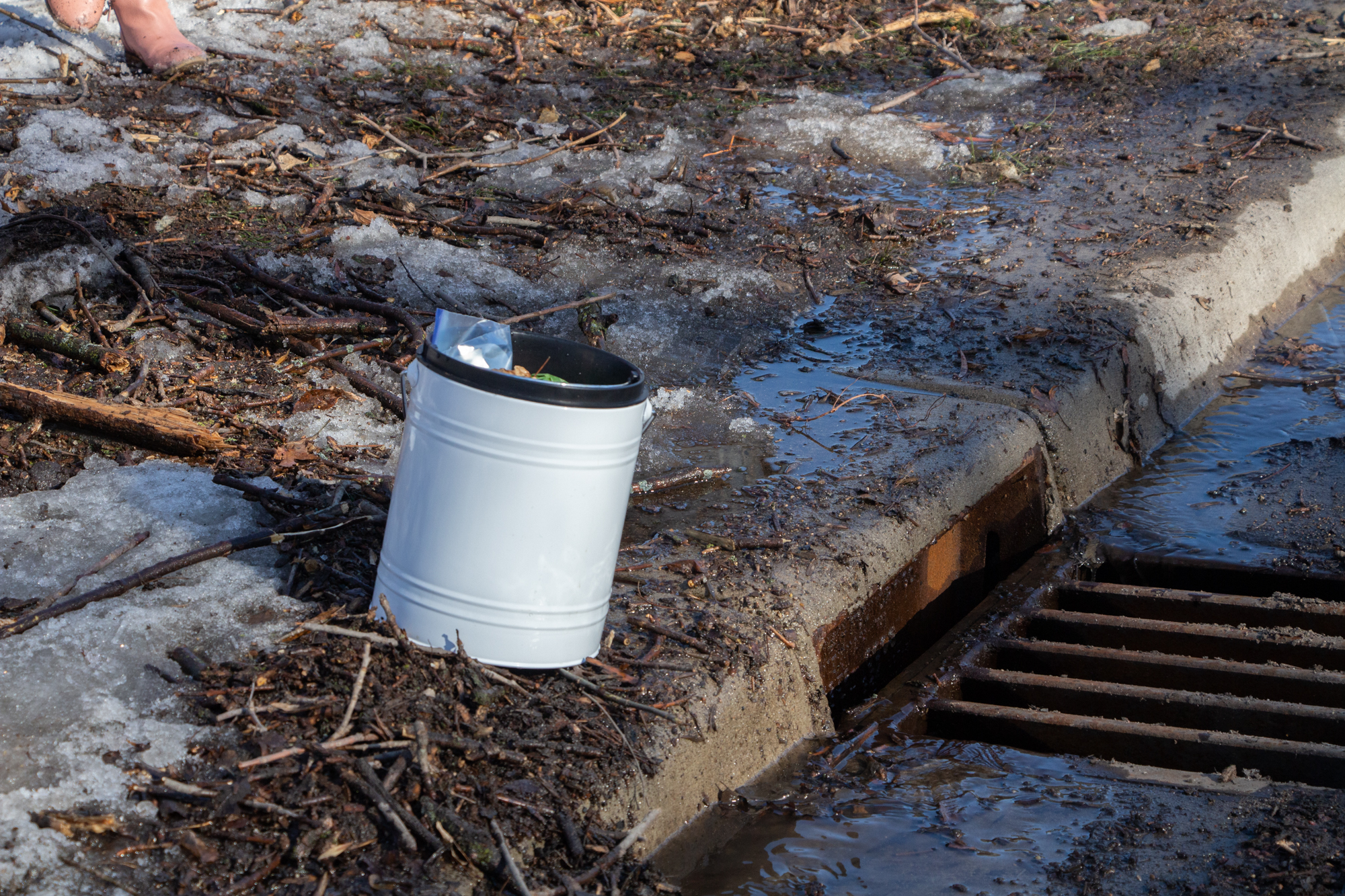 Image slide of Bucket near storm drain with trash